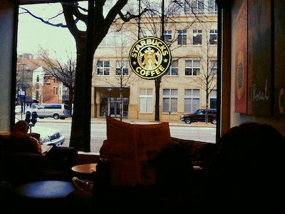 Inside a dimly lit Starbucks store looking through window, outside across street